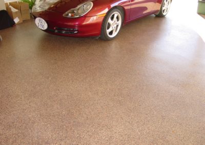 A red car parked in the middle of a garage.