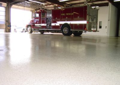 A fire truck parked in the garage of a building.