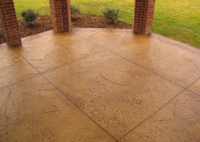 A patio with a brick pillar and grass