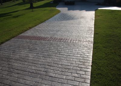 A brick walkway with grass growing on it.