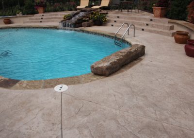 A pool with steps and water features in the back.