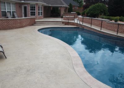 A pool with a brick wall and steps leading to the pool.