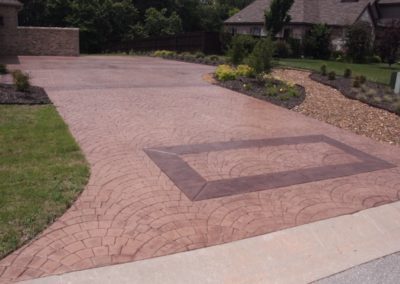 A driveway with a large brick pattern and a stone border.