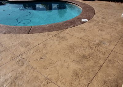 A pool with a blue water and brown concrete