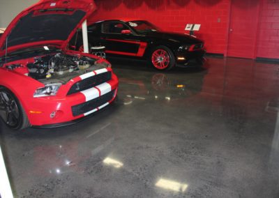 A red and black car in a garage with two other cars.