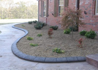 A brick house with a flower bed and a sidewalk.