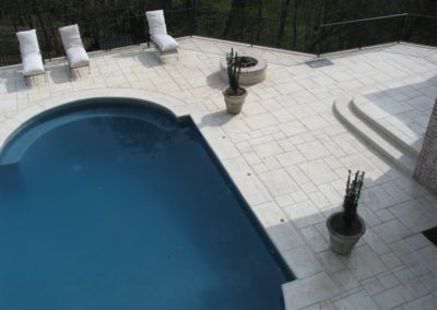 A pool with chairs and potted plants in the middle of it.