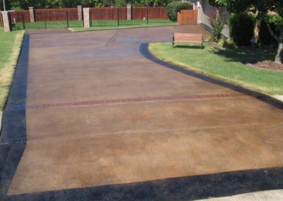 A driveway with brown cement and grass