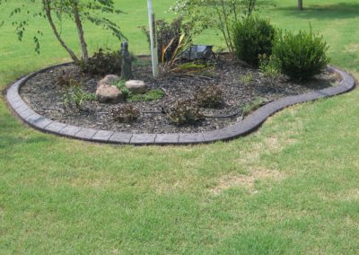 A garden with grass and trees in the background.