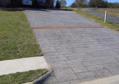 A sidewalk with grass growing on the side of it.