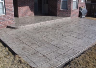 A patio with a brick pattern and concrete.