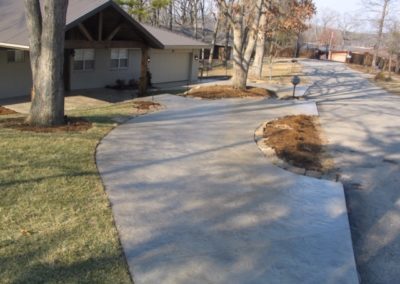 A sidewalk with trees and grass in the background.