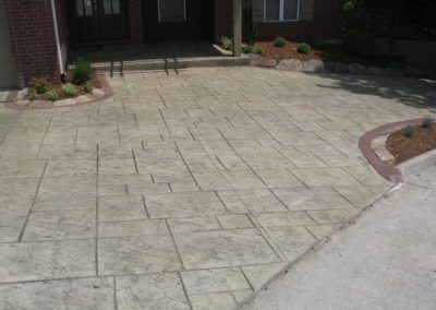 A concrete driveway with red brick border and a circular pattern.