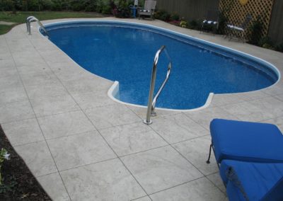 A pool with a blue chair and a white tile floor.