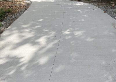 A concrete driveway in the middle of a wooded area.